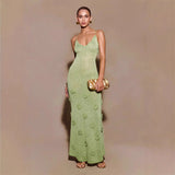 Donna in abito lungo verde con dettagli floreali, borsa dorata e sandali. Moda elegante, abbigliamento da sera, stile sofisticato.